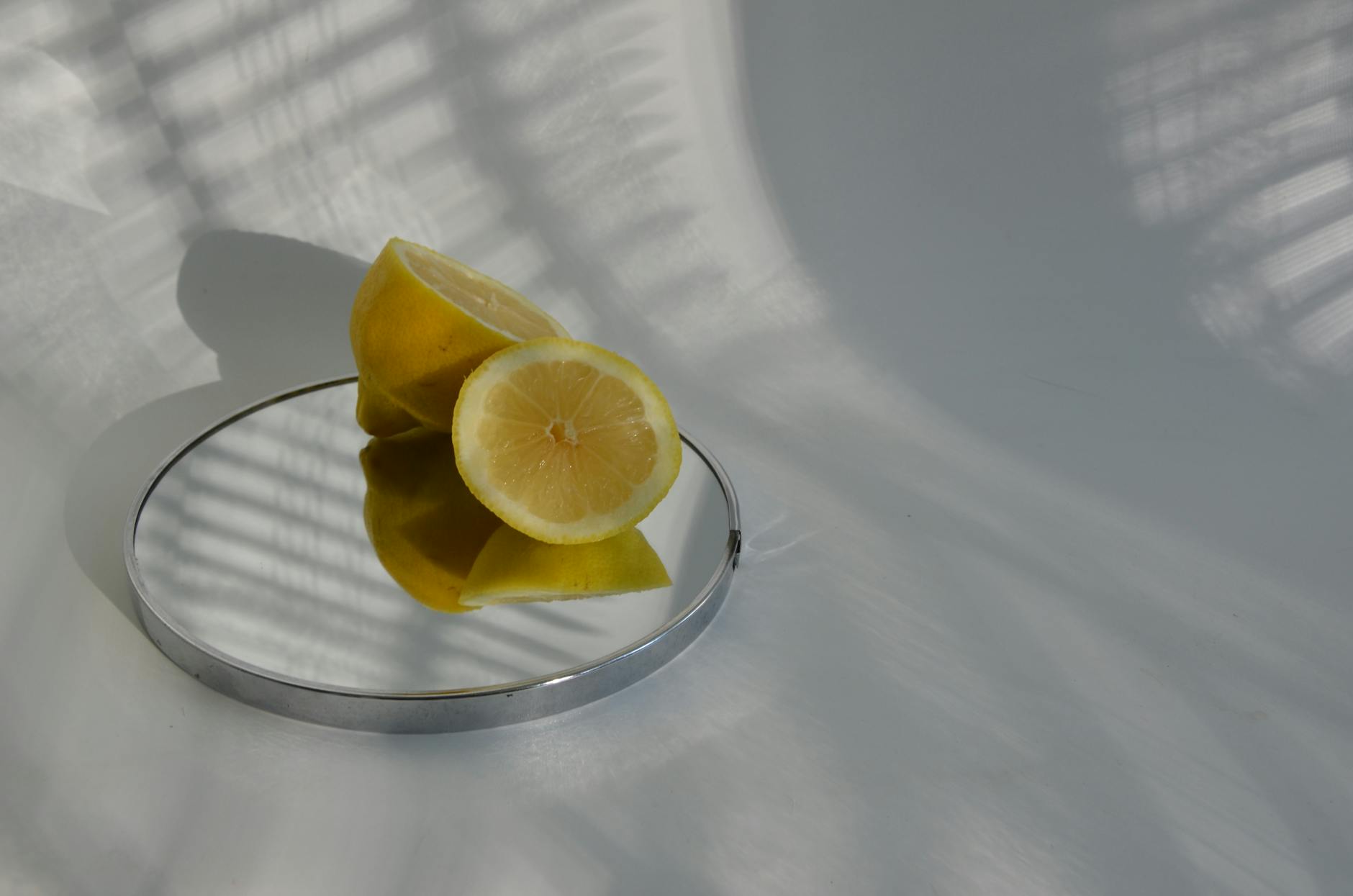 Limões fatiados em um espelho refletindo sombras, mostrando fotografia de alimentos minimalista