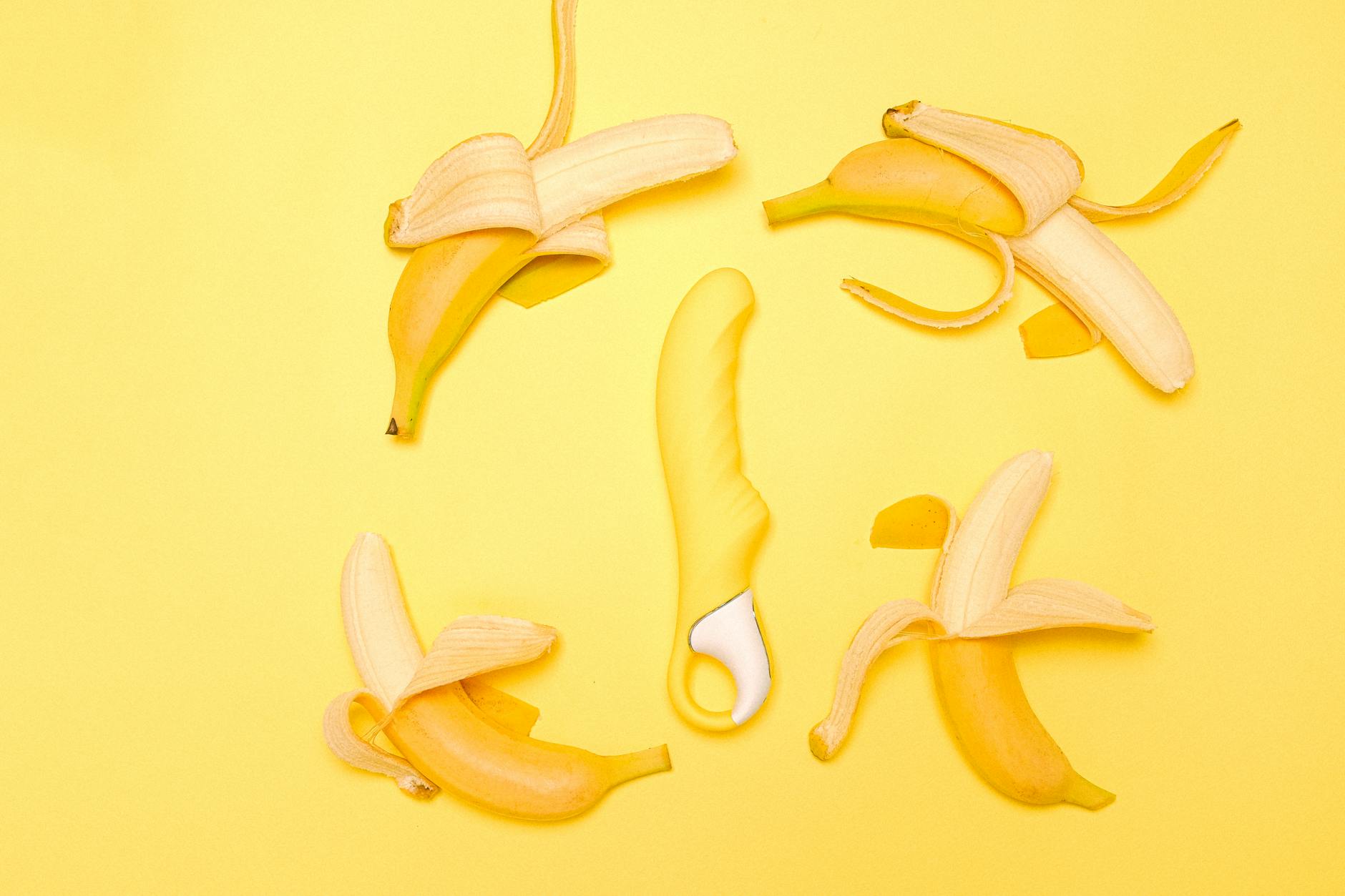 Vibrador de limão amarelo em composição flatlay com bananas e fundo amarelo vibrante