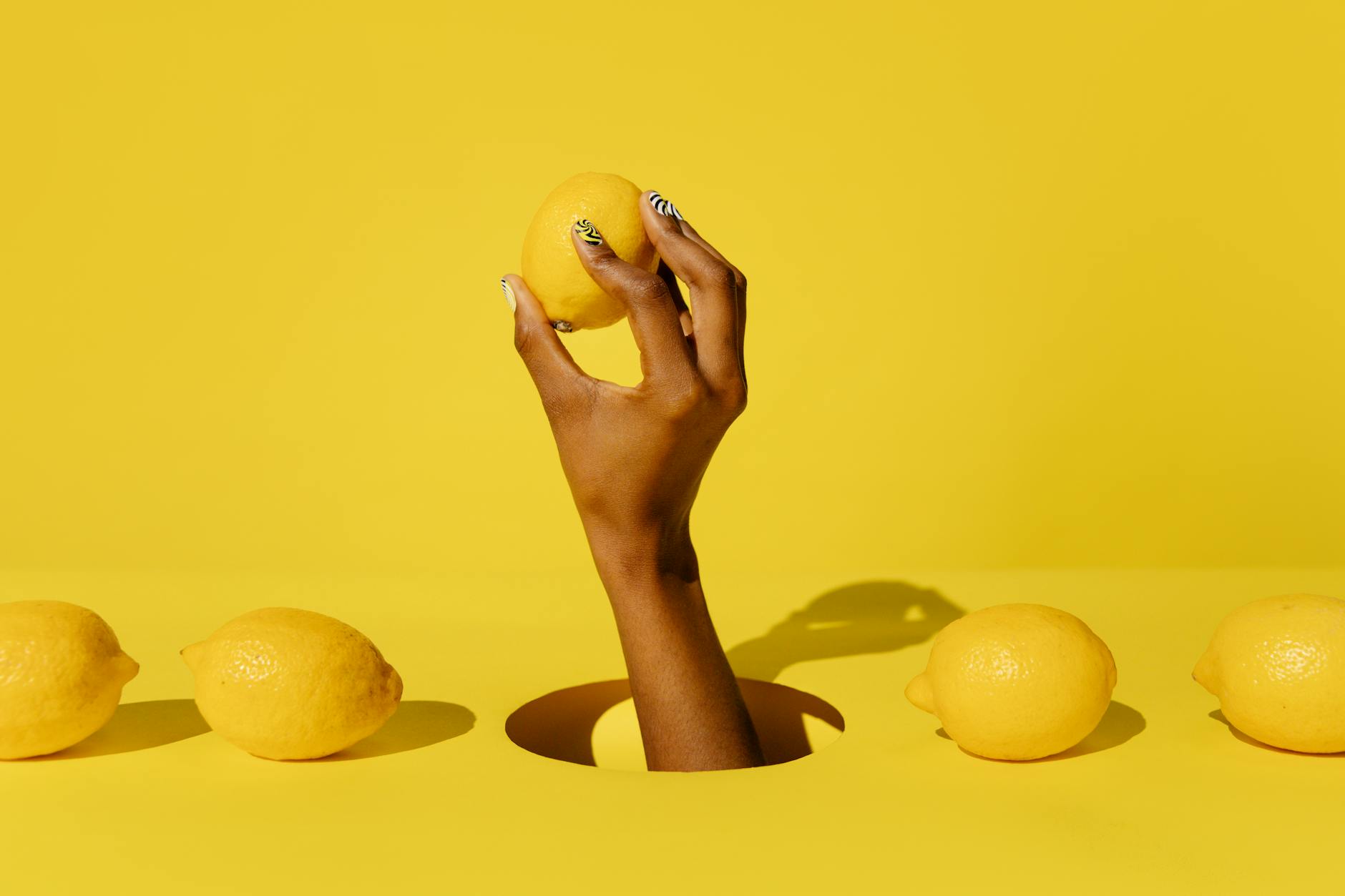 A hand holding a bright yellow lemon against a vivid yellow background, symbolizing fresh arousal strategies