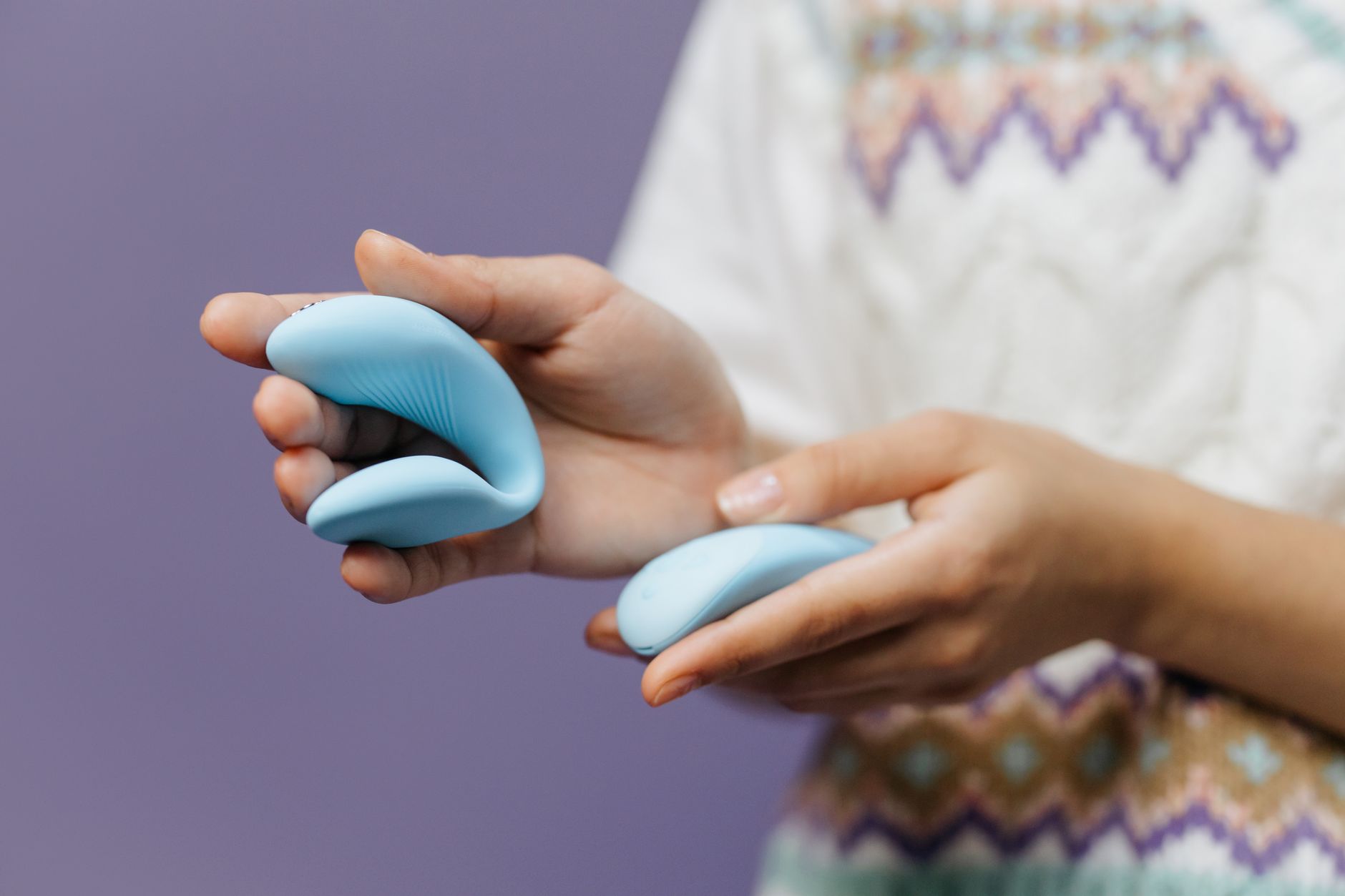Casal jovem de mãos dadas segurando um vibrador azul moderno, representando intimidade e exploração conjunta