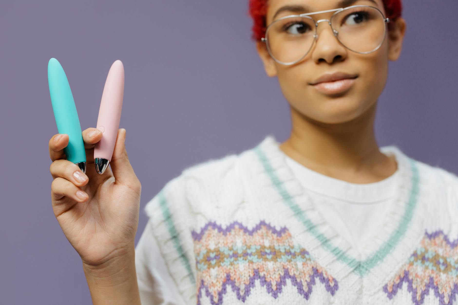 Mulher segurando dois vibradores de limão coloridos em fundo roxo