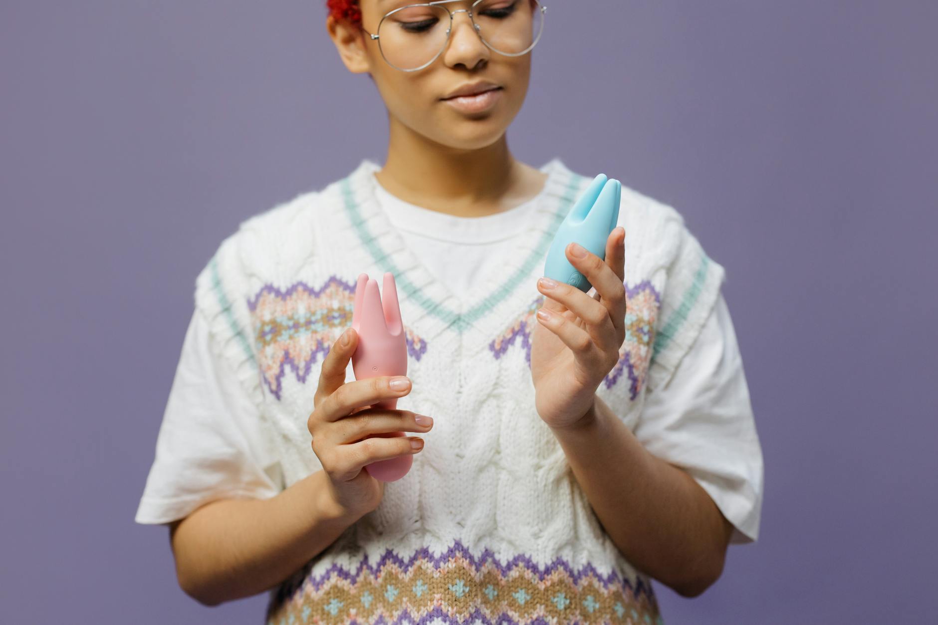 Mãos segurando vibrador azul e rosa com expressão pensativa