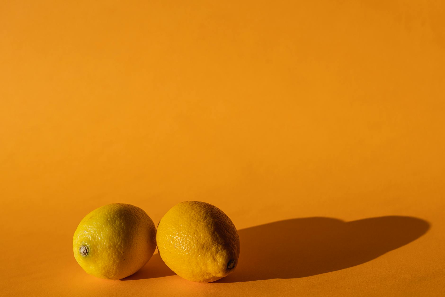 A yellow silicone clitoral vibrator surrounded by peeled fruit on a bright yellow background
